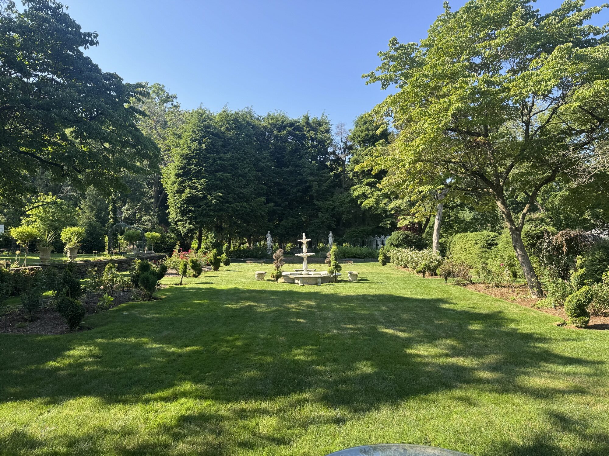 Formal garden with a stone fountain, statuary, and manicured hedges