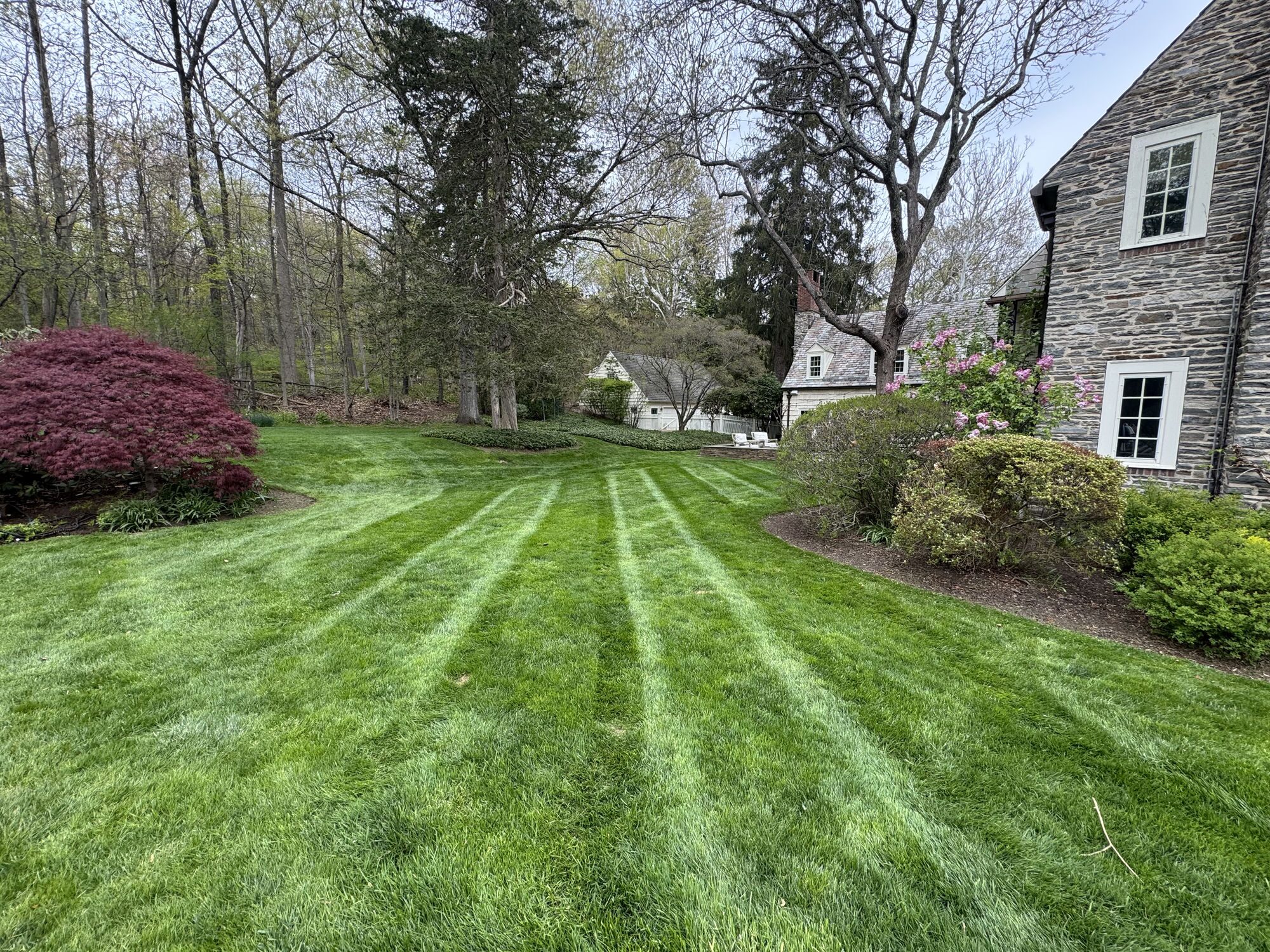 Large stone and shingle home with a manicured, striped lawn